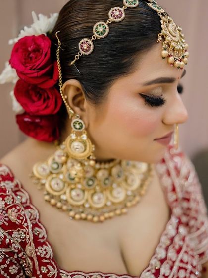 A close-up profile of this beautiful bride's hair and makeup. The classic winged eyeliner and the traditional bun adorned with fresh red roses create a timeless and elegant bridal style.