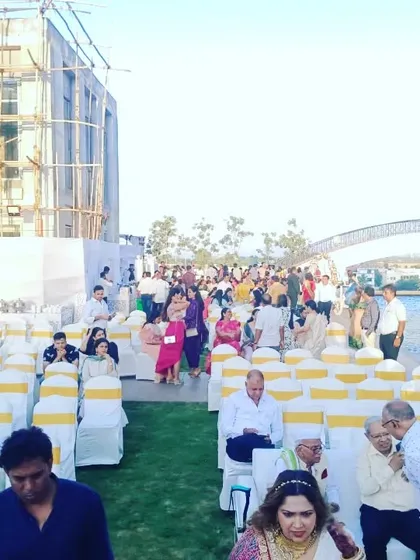 Guest seating at an outdoor, waterside venue. We arranged rows of chairs with white covers and yellow sashes on a green lawn, ensuring guests have a comfortable view of the ceremony.