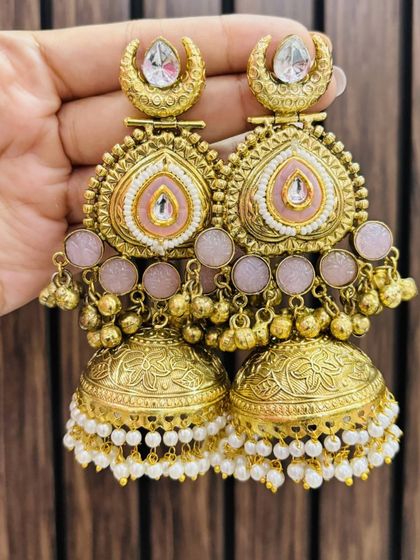 Beautifully crafted gold-plated jhumkas with delicate pink enamel work and pearl drops. A very feminine and elegant choice.