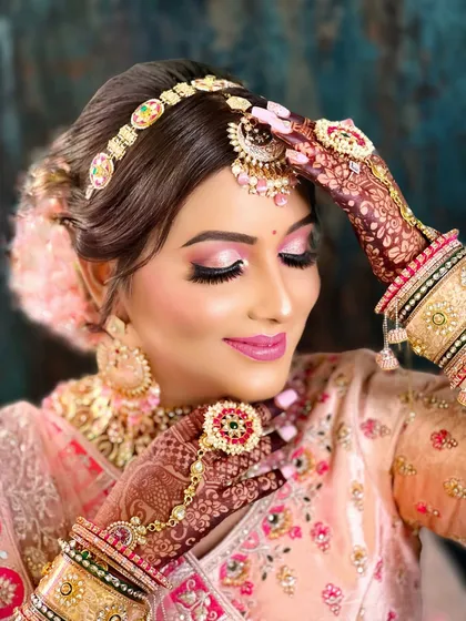 A graceful pose that highlights the maang tikka and the large, ornate earrings of this bridal set.