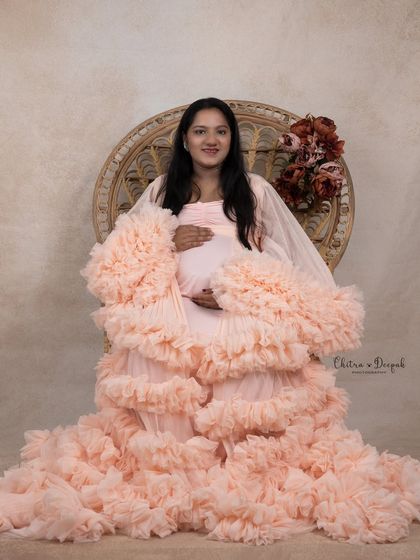Soft and dreamy in peach. This incredibly detailed ruffled gown creates a cloud-like effect, perfect for a gentle and romantic fine-art maternity portrait.