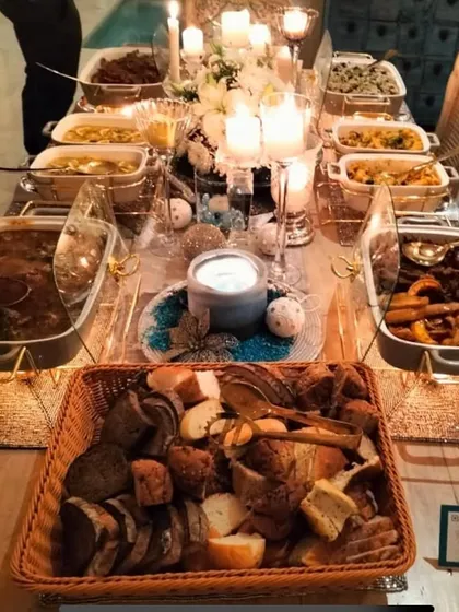 A full view of the Christmas party spread, showing the abundance of food and the warm, candlelit ambiance.