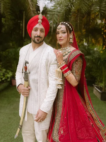 A classic portrait of the Sikh bride and groom in their wedding attire. The groom holds the traditional kirpan, and the bride stands by his side, the picture of elegance.