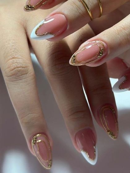 A glamorous set with a white and gold glitter French tip, with intricate gold chrome framing.