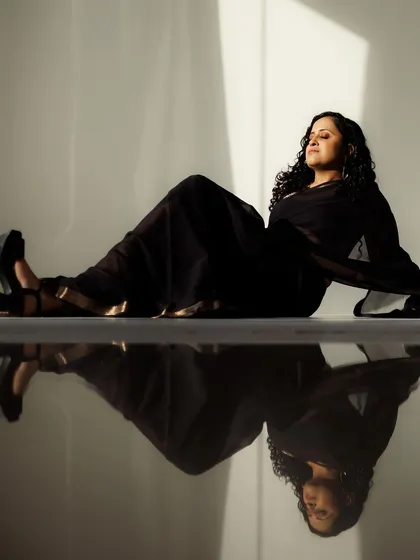 I love playing with light and shadow in photoshoots. This artistic shot captures a modern, elegant look with a sheer black saree. The makeup is subtle and glowing, and the reflection on the floor adds a beautiful, dramatic effect to the overall composition.
