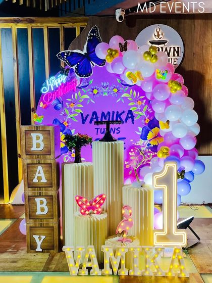 The complete setup for Vamika's first birthday, featuring the purple butterfly theme with a custom backdrop, balloon arch, props, and light-up elements.