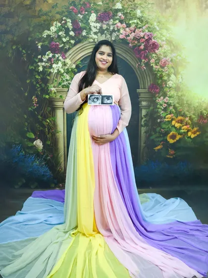 Celebrating double the joy. This mom-to-be looks radiant in our special rainbow gown, proudly showing the first picture of her twins. We have lots of creative ideas for twin maternity sessions.