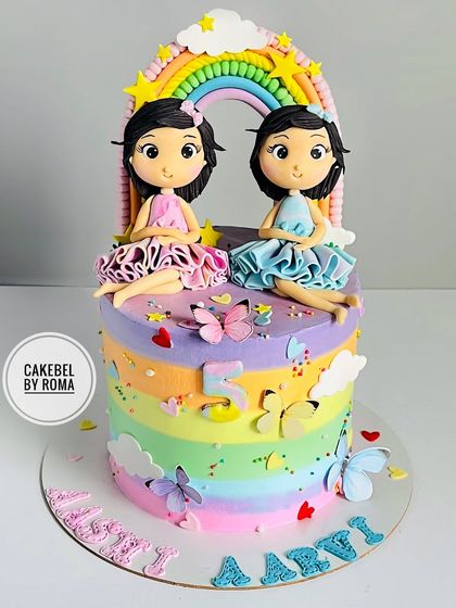 Double the joy for twin sisters. This rainbow cake is topped with two custom-made fondant figurines, designed to look just like the birthday girls, sitting under a colorful rainbow arch.