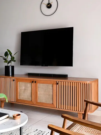 This custom-built media console is simple, minimal, and elegant. The combination of fluted wood and rattan on the shutters keeps electronic devices discreetly stored for a clutter-free look.
