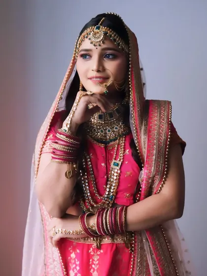 A thoughtful pose showcasing the full bridal attire. The makeup is balanced to work with the heavy jewelry and embroidered outfit.