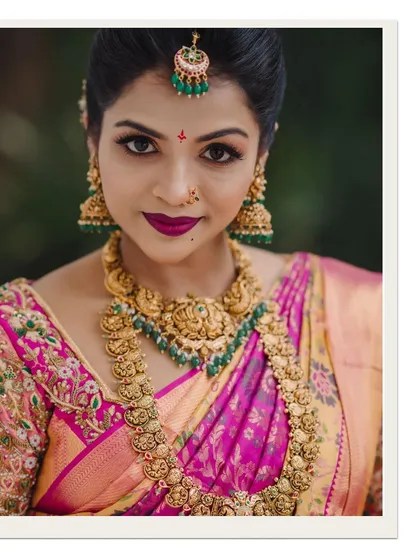 A striking close-up of a South Indian bride, showcasing her flawless makeup, intricate gold jewelry, and the vibrant colors of her wedding saree. Her confident gaze is captivating.