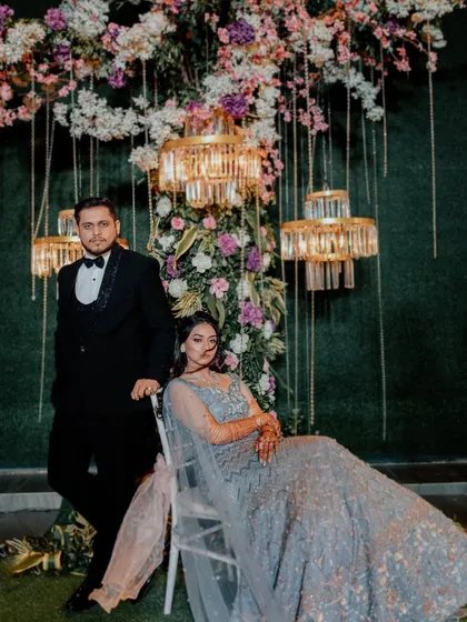 A formal portrait of Dhwnai and Niraj against a stunning floral and chandelier backdrop, showcasing the grandeur of their engagement decor.