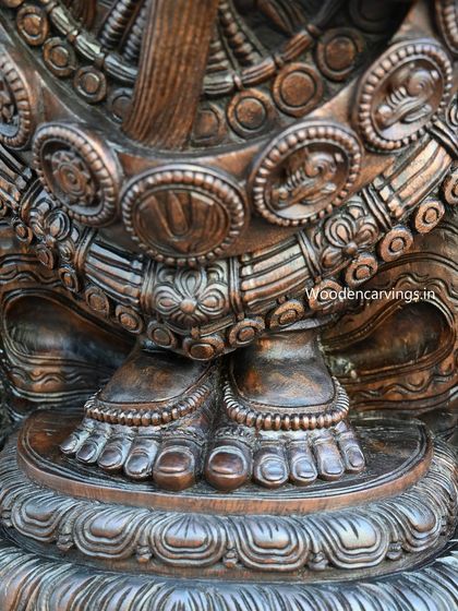 A close-up of the feet of the Lord Venkatajalapathy statue, resting on a lotus pedestal, showcasing the detailed carving of the anklets and toes.