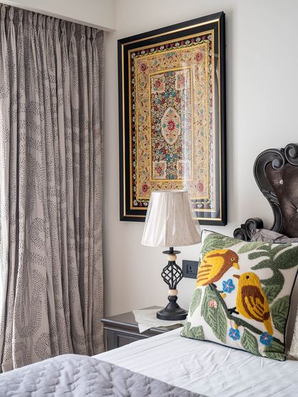 A detail shot from the 'Eternity' bedroom, focusing on the rich textures. The tufted headboard, embroidered bird cushion, and traditional framed art create a classic and comfortable corner.