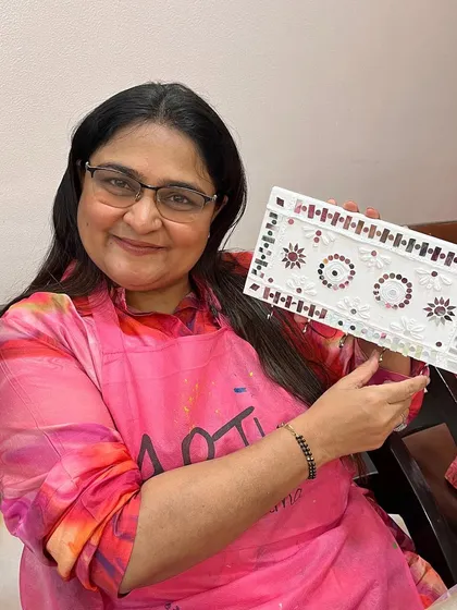 A happy guest showing her intricate white Lippan art key holder. Even beginners can create stunning pieces with guided instruction.