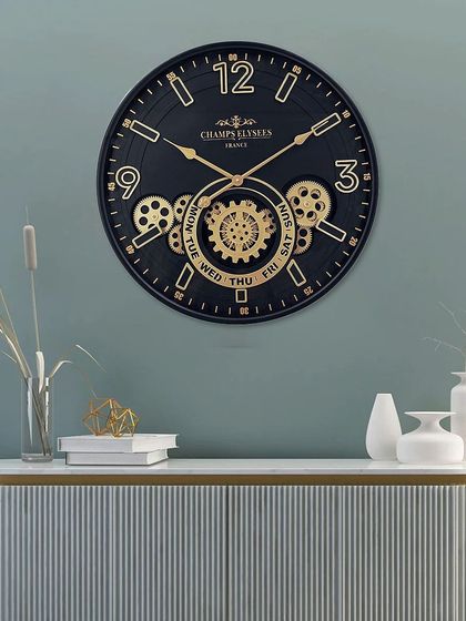 This modern black wall clock features a calendar function for the day and date within its moving gear mechanism. The clean lines and gold accents make it a chic and functional addition to any office or home.
