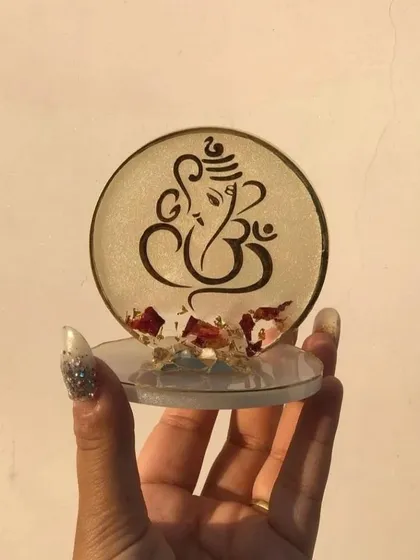 This mini Ganesha stand features a clear base with delicate dried flower petals embedded in the resin. It's a beautiful and serene design, perfect as a small token of appreciation.