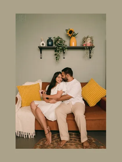 A comfortable and sweet embrace on the couch during an indoor pre-wedding shoot. The warm tones and home-like setup create a feeling of genuine intimacy.