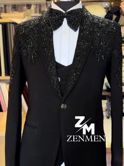 A full view of the heavily beaded black tuxedo. The matching bow tie and embellished shoulders create a powerful and cohesive statement look.
