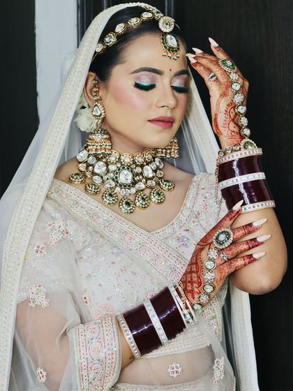 The bride showing off her full bridal look, including the chooda and mehndi.
