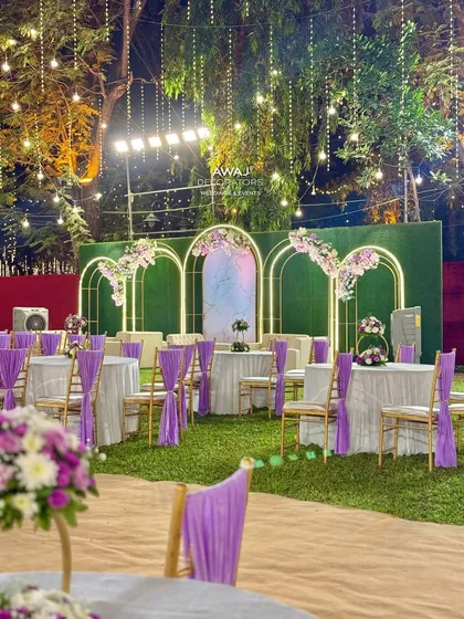 A wide view of the guest dining area, with beautifully decorated tables and chairs set on a lush green lawn.