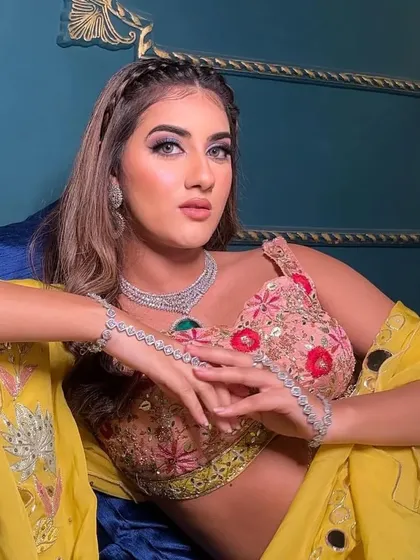 This model showcases a modern party look, pairing a floral blouse with a zircon necklace that features a large green stone. It's a perfect set for making an entrance at a sangeet or cocktail night.