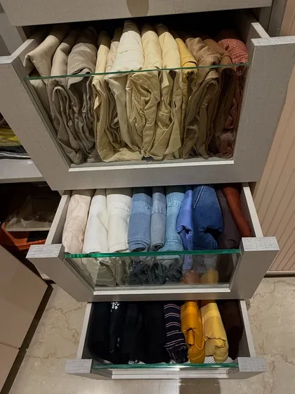 Three drawers pulled open to showcase how we organize different types of trousers. From light-colored linens to dark denim, each category is grouped and folded for maximum visibility and space efficiency.