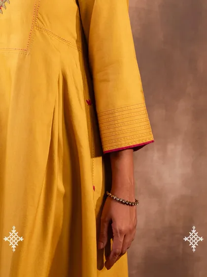 The details make the design. This image shows the fine quilting on the shoulder and the neat finish of the sleeve hem on our Ruhani Yellow Pleated Kurta, reflecting the care put into every garment.