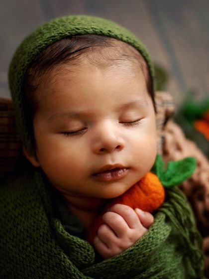 A close-up of the little one, all wrapped up and holding a tiny carrot. I make sure every baby is warm, safe, and comfortable in every pose.