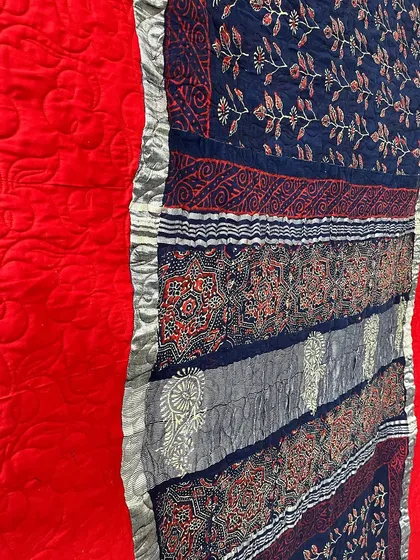 A close-up of the intricate patterns within the red and blue saree quilt.