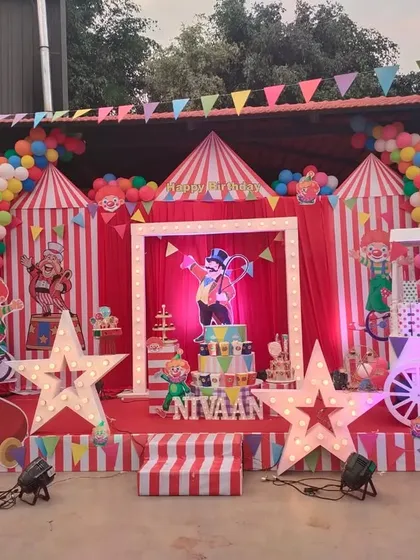 Step right up to a spectacular carnival-themed 5th birthday party. This grand outdoor setup features a classic red and white striped circus tent backdrop, light-up star props, a ticket booth-style cart, and fun clown cutouts to bring the big top to life.
