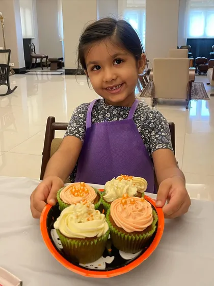 A very happy baker showing off her beautifully decorated Halloween cupcakes. We use natural colors for our frosting, so they are as good to eat as they look.