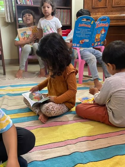 A group of children reading together on the floor, each exploring a different book. Our collection has something for every interest.
