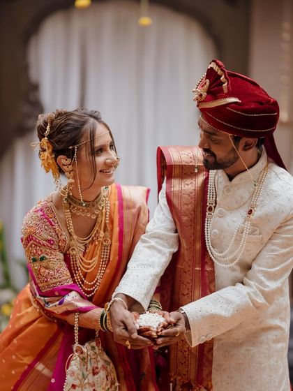 A beautiful moment from a Marathi wedding ceremony, where the couple shares a meaningful ritual, their eyes filled with love and respect.