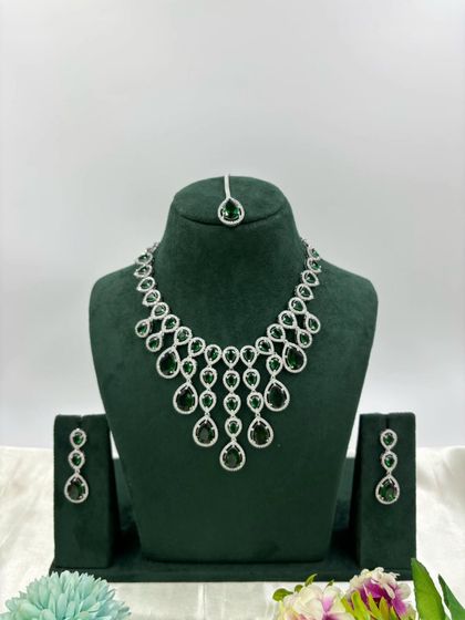 An elegant AD necklace set with a matching maang tikka. The cascading design with teardrop stones is available in green, pink, and all-white, perfect for receptions and parties.