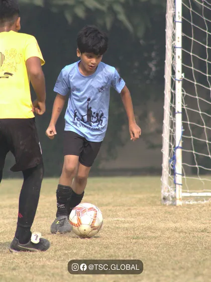 A young player dribbles the ball with intense focus during a School Soccer League match.