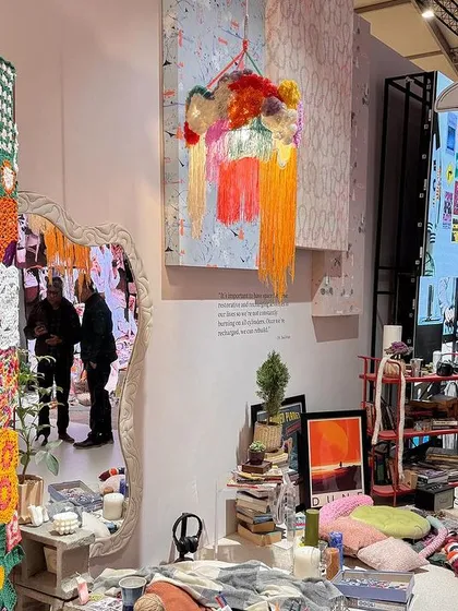 The 'Goblin Mode' installation, a response to intense productivity culture. This view shows a totem-like sculpture covered in colorful crochet, part of a space designed for informal comfort and self-indulgence.