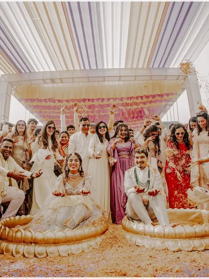 The couple seated in large lotus-shaped pots for the ritual. This unique setup for Rahul and Riya's Haldi ceremony made for some incredible photos, surrounded by their cheering friends and family.