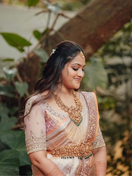 A close-up of the bride, showcasing her traditional temple jewelry and the subtle yet intricate embroidery on her blouse.
