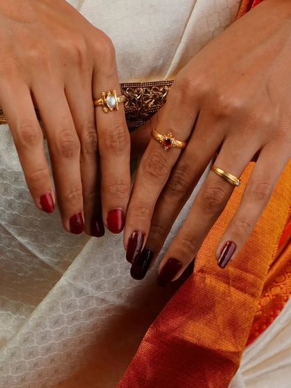 A close-up on the hands, showcasing the various rings and the deep red manicure. This kind of detailed shot adds a lifestyle element to a fashion or jewelry series, telling a more complete story about the overall look.