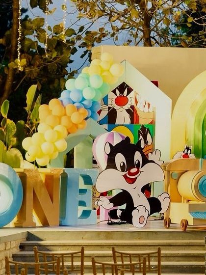 A close-up of the Looney Tunes first birthday setup, with "ONE" blocks and cutouts of baby Sylvester and Daffy.