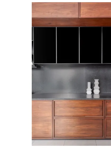 A detail of the kitchen cabinetry in the Bombay Penthouse. The contrast between the warm teak, the dark glass, and the cool granite backsplash is a study in material harmony.