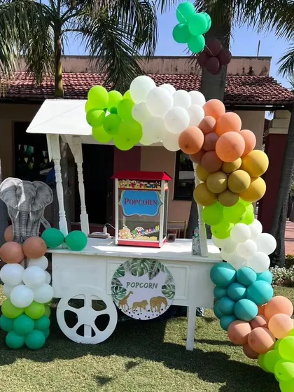 A themed popcorn cart decorated with a jungle-style balloon arch, adding a fun element to the outdoor party.