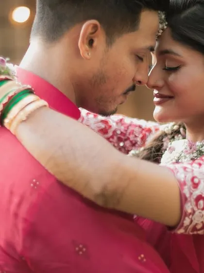 An intimate close-up of a couple in vibrant red traditional outfits, capturing a tender moment before their wedding.