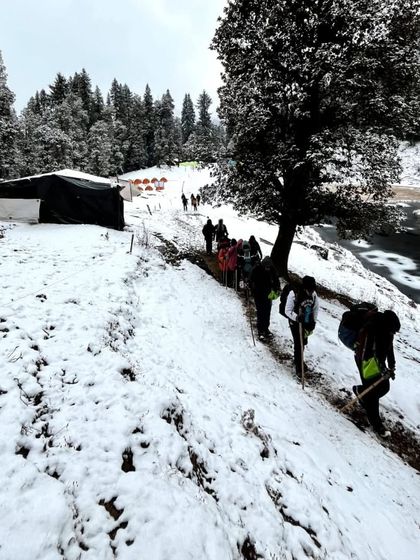 The team making their way through the snow, leaving the campsite behind. Our experienced trek leads guide you every step of the way, ensuring your safety.