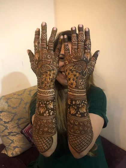 A playful shot of a bride showing off her full bridal mehendi, complete with peacocks and lotuses.