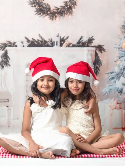 Holiday photos are even more fun with friends. This shot captures two girls sharing a hug in our cozy Christmas fireplace setting.