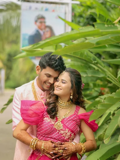 A happy couple portrait from a wedding event, framed by lush green leaves.