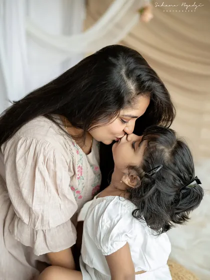 A sweet kiss between mother and daughter. These are the tender, everyday moments that create the most cherished memories.