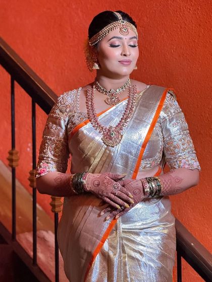 A serene moment captured on the stairs. The soft lighting highlights the beautiful shimmer of her saree and the flawless finish of her makeup.